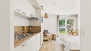 A modern kitchen with a wooden countertop, a built-in oven, and a dining area with a table and chairs. - Le Nose Rider - studio for 3 - shared pool (Biscarrosse)