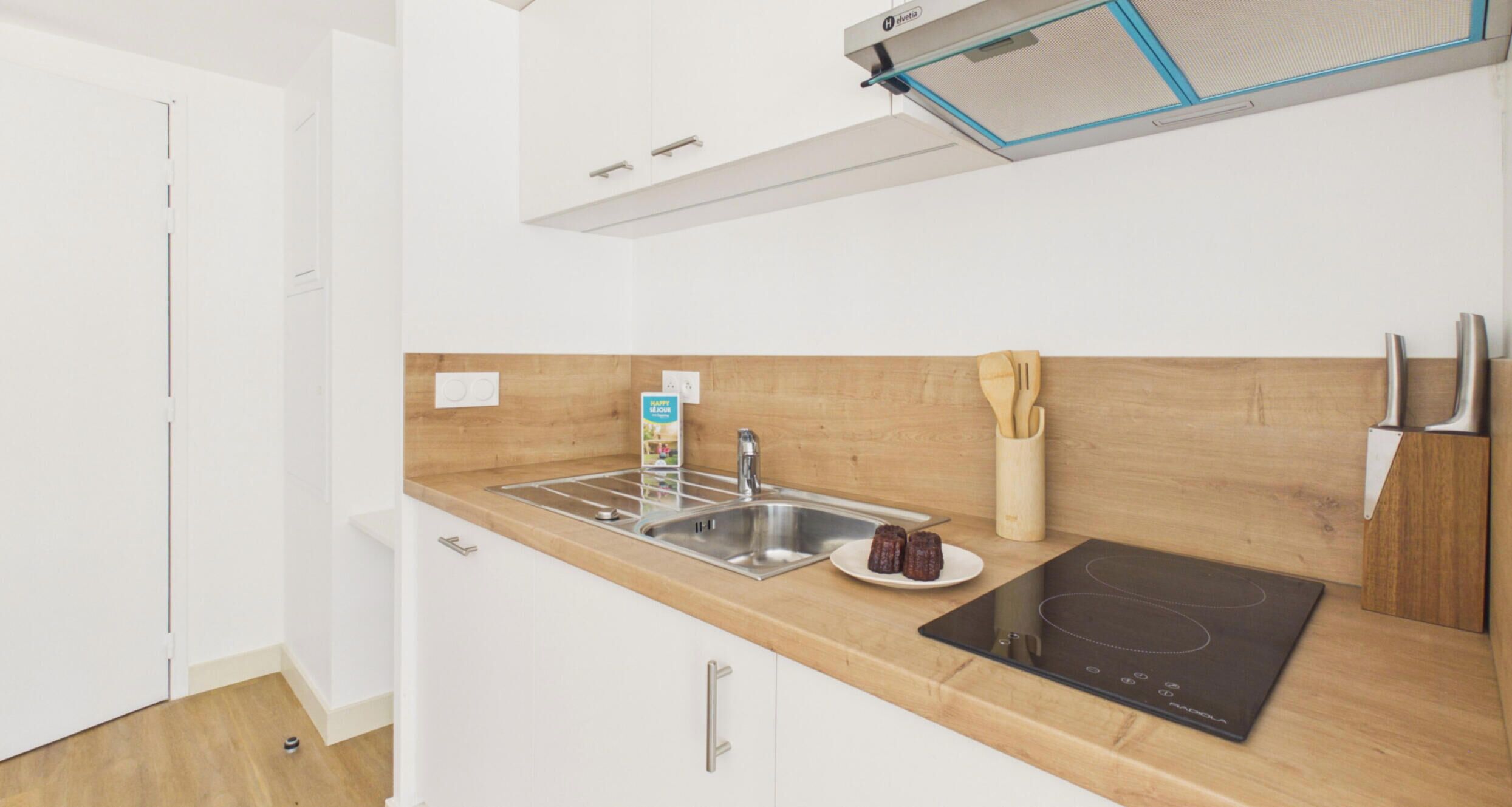 A modern kitchen with a wooden countertop, stainless steel sink, and a black induction cooktop.