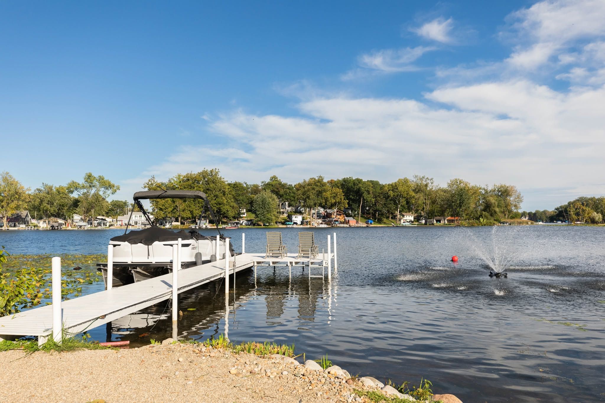 A lakeside dock with a boat, a jet ski, and a clear sky.