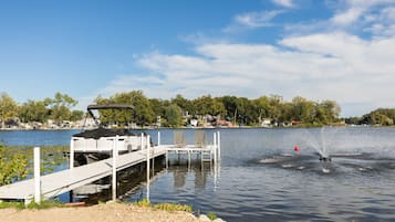 A lakeside dock with a boat, a jet ski, and a clear sky.