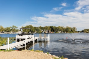 A lakeside dock with a boat, a jet ski, and a clear sky. - Sunrise on Sawmill - Kayaks, Paddleboat, Firepit, Arcade! (Leesburg)