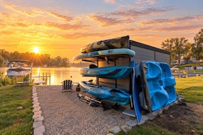 Un chalet au bord du lac, avec des kayaks et une planche de paddle rangés sur un support.