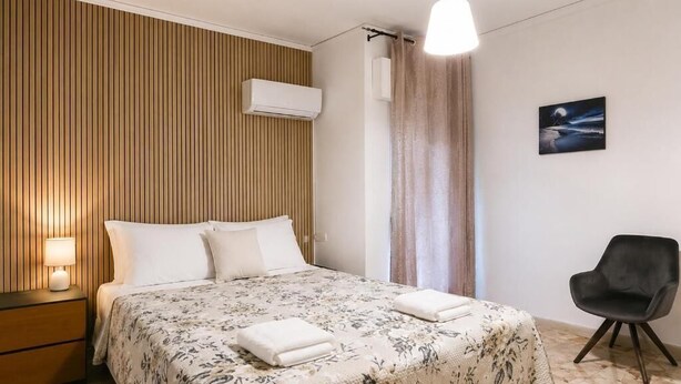 A hotel room with a bed, a nightstand, a chair, a wall-mounted air conditioner, and a painting. - BnB Short-term rental Palermo Center, vacation home apartment (Palermo)