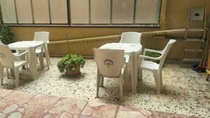 A patio area with white plastic chairs and tables, a potted plant, and a ladder. - BnB Short-term rental Palermo Center, vacation home apartment (Palermo)