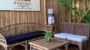 Quarto com decoração em bambu, possui um sofá, uma mesinha e um lustre.