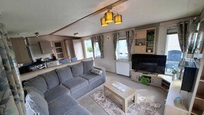 Een compacte woonruimte met een bank, televisie, kitchenette en een eethoek.