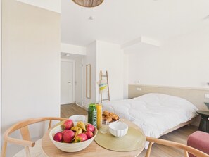A hotel room with a bed, a breakfast table with fruits, a bottle, and a bowl. - Le Mid-Length - studio for 3 - shared pool (Biscarrosse)