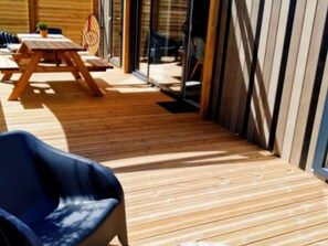 Una terraza de madera con una silla azul, una mesa de picnic y una pequeña planta en maceta.