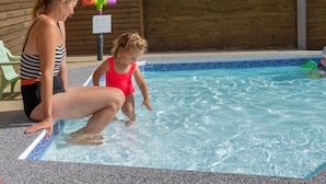 Ein Poolbereich mit einer Holzverkleidung, einem grünen Stuhl und einem bunten Wasserspielzeug.