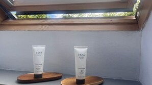 Een dakraam met twee tubes ESPA body wash en conditioner op houten voetstukken.