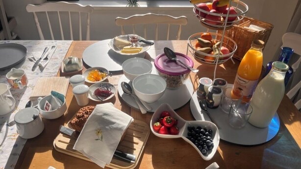 Een ontbijttafel gedekt met diverse gerechten, waaronder fruit, brood en drankjes.