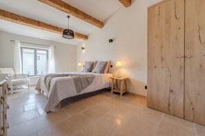 Ein Schlafzimmer mit einem Bett, Nachttischlampen, einem Holzschrank, einem Schminktisch und einem Fenster mit Vorhängen.