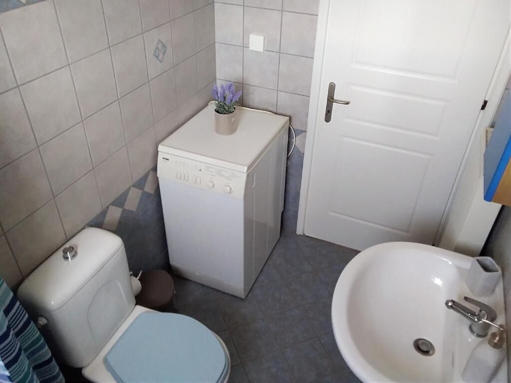 A small bathroom with a toilet, a washing machine, and a sink.