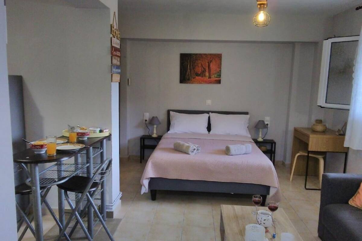 A bedroom with a bed, a desk, a chair, a coffee table, and a painting on the wall.
