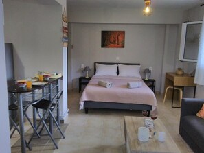 A bedroom with a bed, a desk, a chair, a coffee table, and a painting on the wall. - Casa memories (Kalligoni)