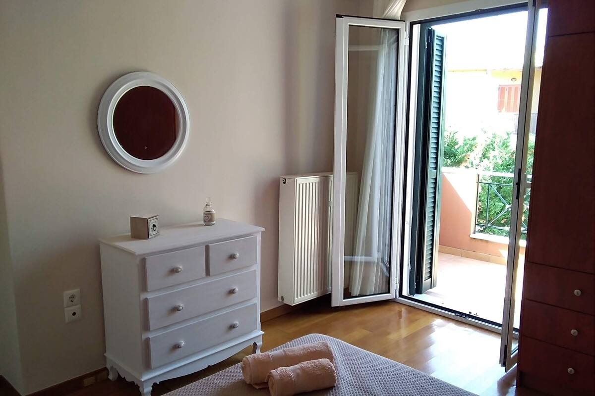 A bedroom with a bed, a dresser, a radiator, and a sliding glass door to a balcony.