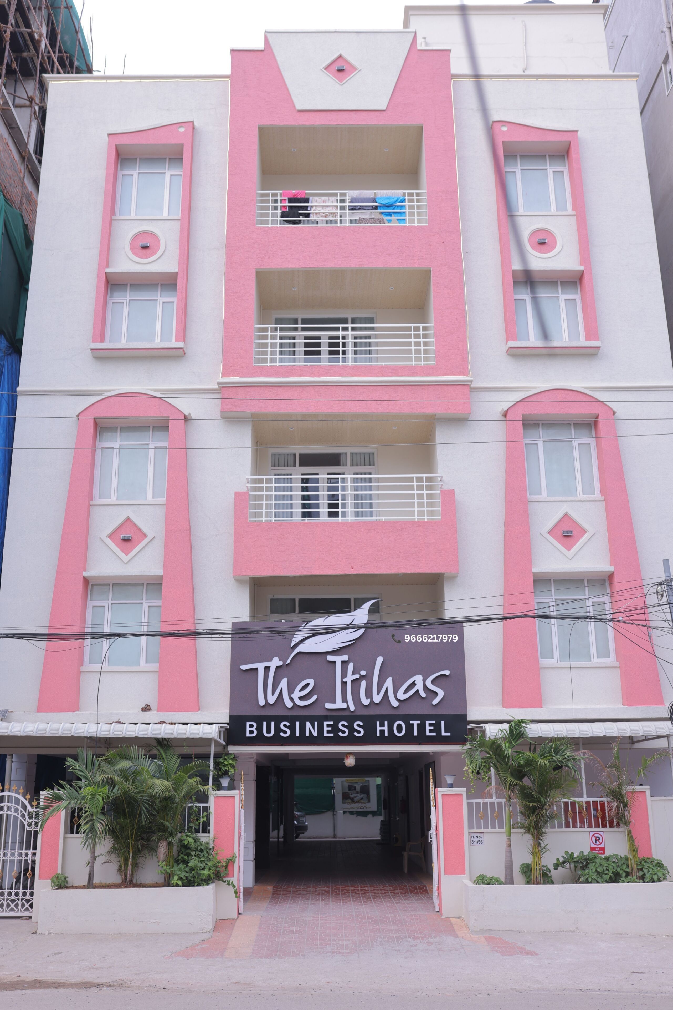 Un edificio de varios pisos con un letrero llamativo para 'The Rihas Business Hotel' al nivel de la calle.