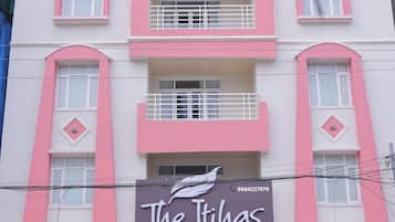 Un edificio de varios pisos con un letrero llamativo para 'The Rihas Business Hotel' al nivel de la calle.