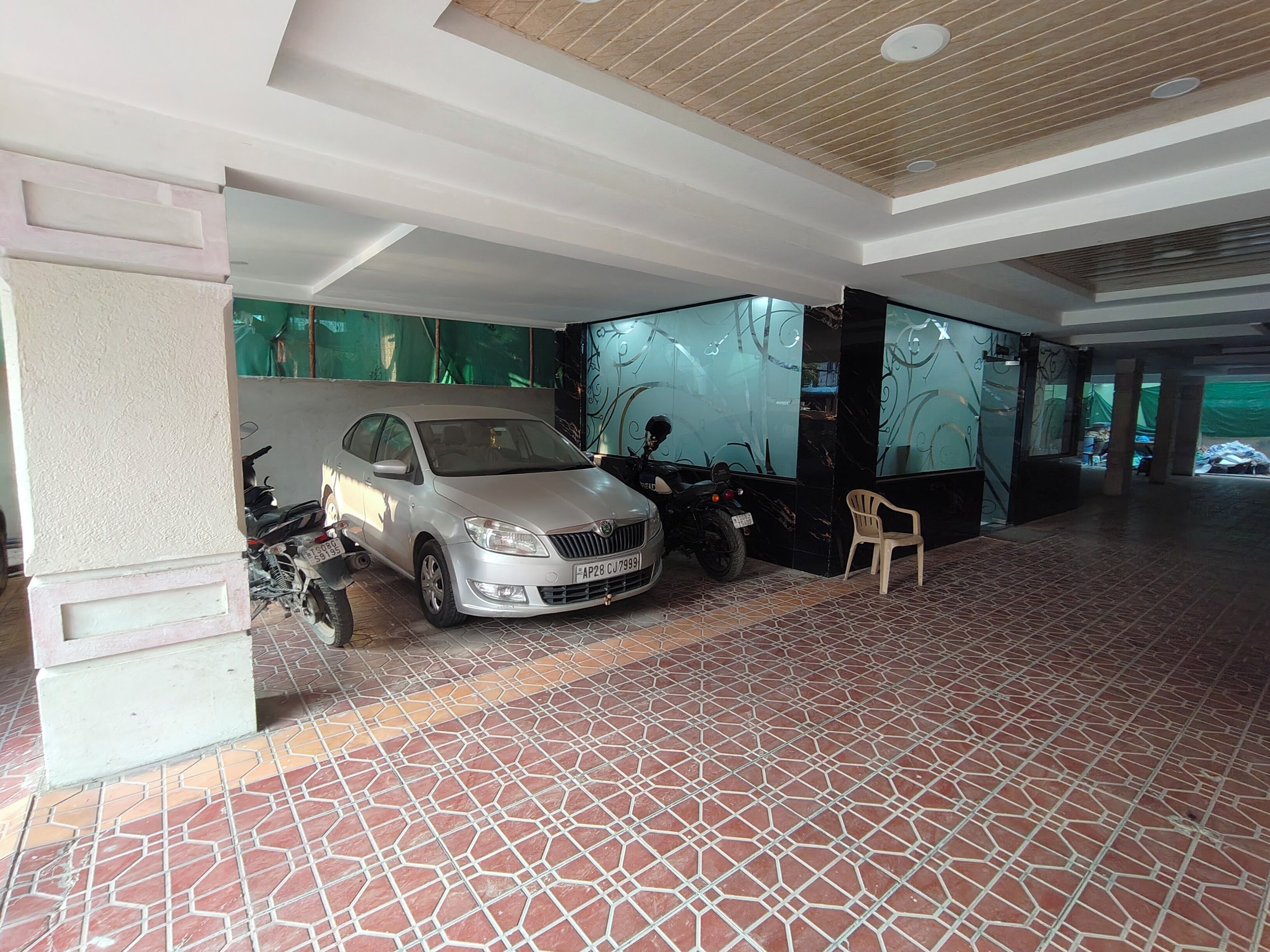 A spacious indoor area with a tiled floor, a parked car, and a motorcycle.