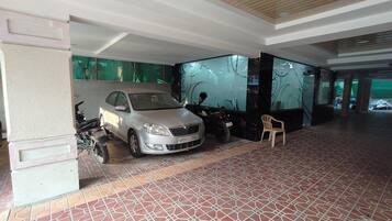 A spacious indoor area with a tiled floor, a parked car, and a motorcycle.