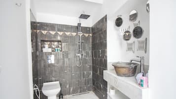 Et moderne badeværelse med bruser, toilet, håndvask og diverse toiletartikler.