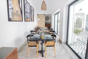 A dining area with a black table, wooden chairs, and a large window. - Dar Dou (Tunis)