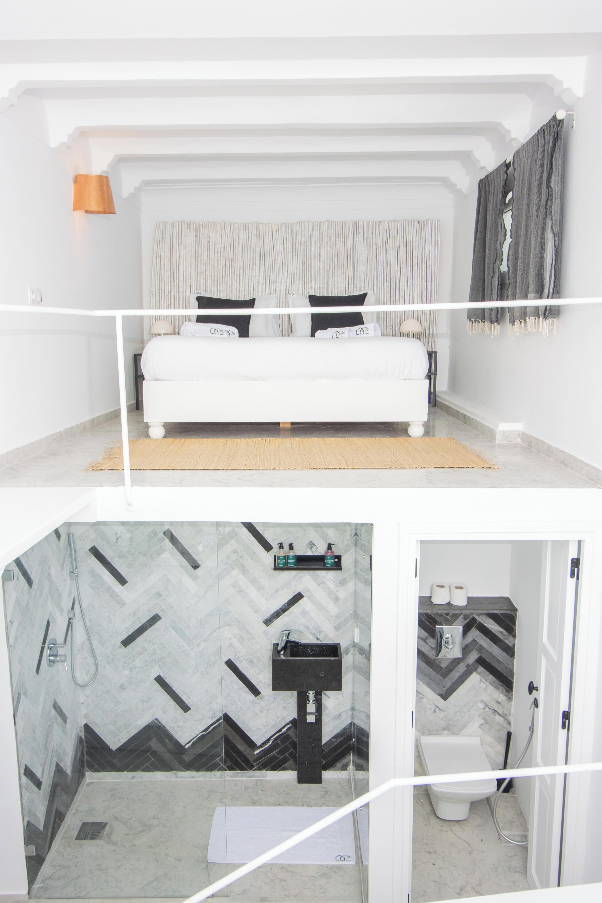 Un dormitorio con cama, un baño con lavamanos e inodoro, y una zona de ducha.