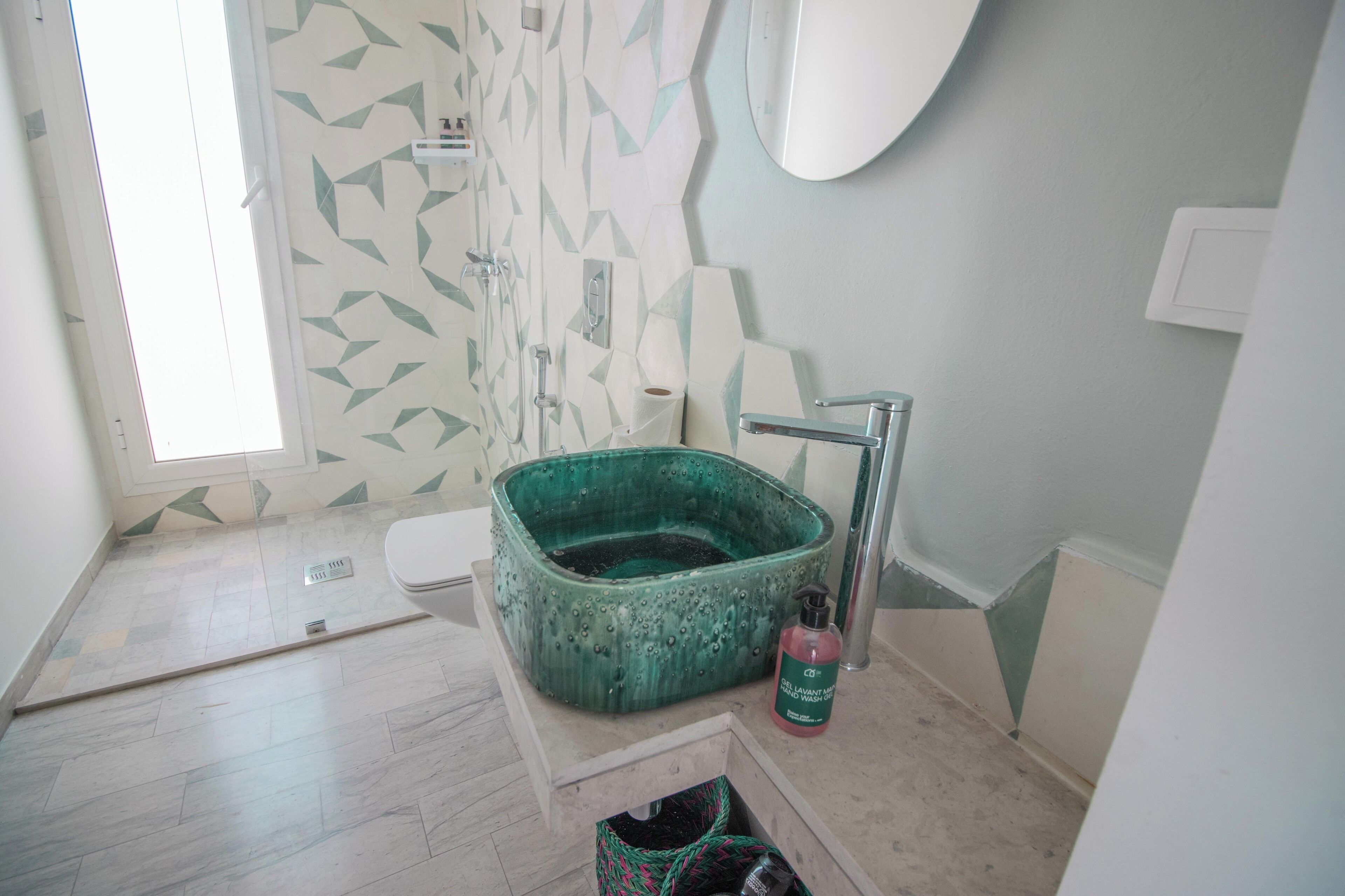 A bathroom with a green ceramic sink, a toilet, and a shower area.