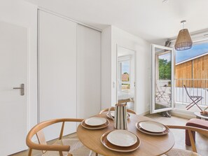 Un'area pranzo moderna con un tavolo di legno apparecchiato per quattro persone, una porta bianca e vista all'esterno.