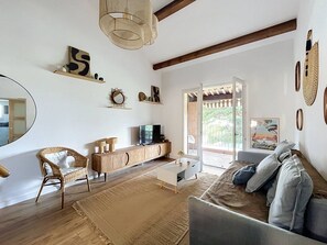 Una sala de estar con sofá, una silla de mimbre, un mueble de madera y un televisor.