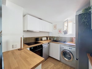 A compact kitchen with a dishwasher, washing machine, and a wooden countertop. - Apartment near beach with parking - 4 guests (Saint-Cyr-sur-Mer)
