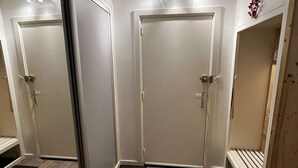 A hotel room with two doors, a bench, and a small wooden cabinet. - Spacious apartment with balcony - 4 guests (Valloire)