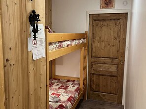 A bunk bed with a quilt, a wooden door, and a wall-mounted light fixture. - Spacious apartment with balcony - 4 guests (Valloire)