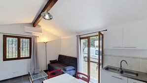 Una cucina compatta con un tavolo da pranzo, sedie, un divano e una porta scorrevole in vetro che dà su uno spazio all'aperto.