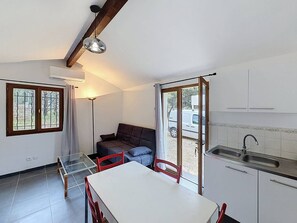 A compact kitchen with a dining table, chairs, a sofa, and a sliding glass door leading to an outdoor area. - Cottage with air conditioning in quiet - 4 guests (La Cadière-d'Azur)