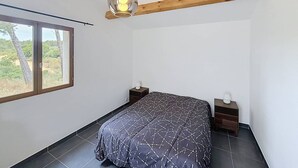 Una camera da letto con un letto, due comodini, una lampada a sospensione e una finestra con vista.