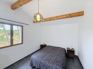 A bedroom with a bed, two bedside tables, a hanging light fixture, and a window with a view. - Cottage with air conditioning in quiet - 4 guests (La Cadière-d'Azur)