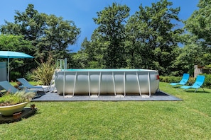 Ein Pool mit Liegestühlen und einer überdachten Liegefläche.