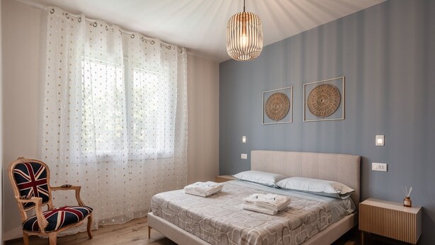 Ein Schlafzimmer mit einem Bett, einem Sessel, einem Nachttisch und einer Pendelleuchte.