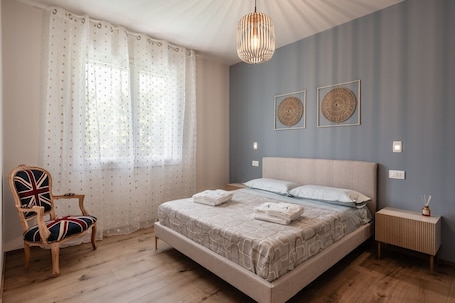 A bedroom with a bed, a chair, a bedside table, and a hanging light fixture.. Apartment 'Corinna' with Mountain View, Wi-Fi and Air Conditioning