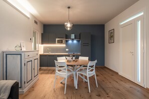Une cuisine moderne avec des meubles blancs, une table à manger en bois et des chaises blanches.