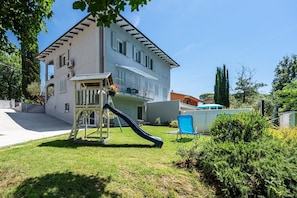 A two-story building with a balcony, a slide, and a patio area with a chair.