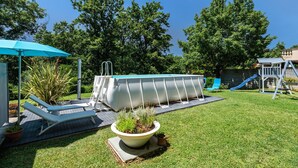 A backyard with a swimming pool, lounge chairs, a small garden, and a slide. - Apartment 'Virginia' with Mountain View, Shared Pool and Wi-Fi (Bosco di Piccione)