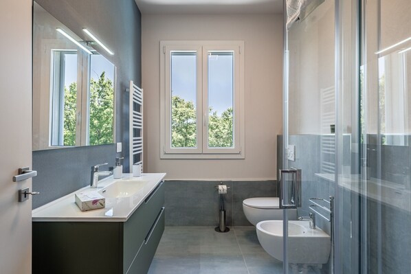 A modern bathroom with a large mirror, a sink, a toilet, and a shower area.