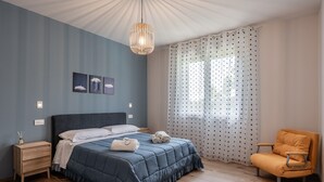 A bedroom with a bed, a nightstand, a chair, a ceiling light, and a window with curtains. - Apartment 'Virginia' with Mountain View, Shared Pool and Wi-Fi (Bosco di Piccione)