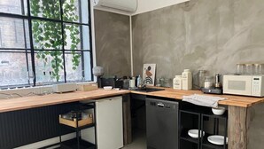 Cozinha compacta com bancada de madeira, lava-louças, micro-ondas e janela com vista para o verde.