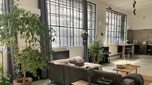 Uma sala de estar moderna com um sofá, uma máquina de escrever e uma janela grande.