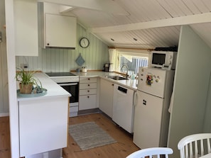 Una cucina compatta con mobili bianchi, un fornello, un forno a microonde e un frigorifero.