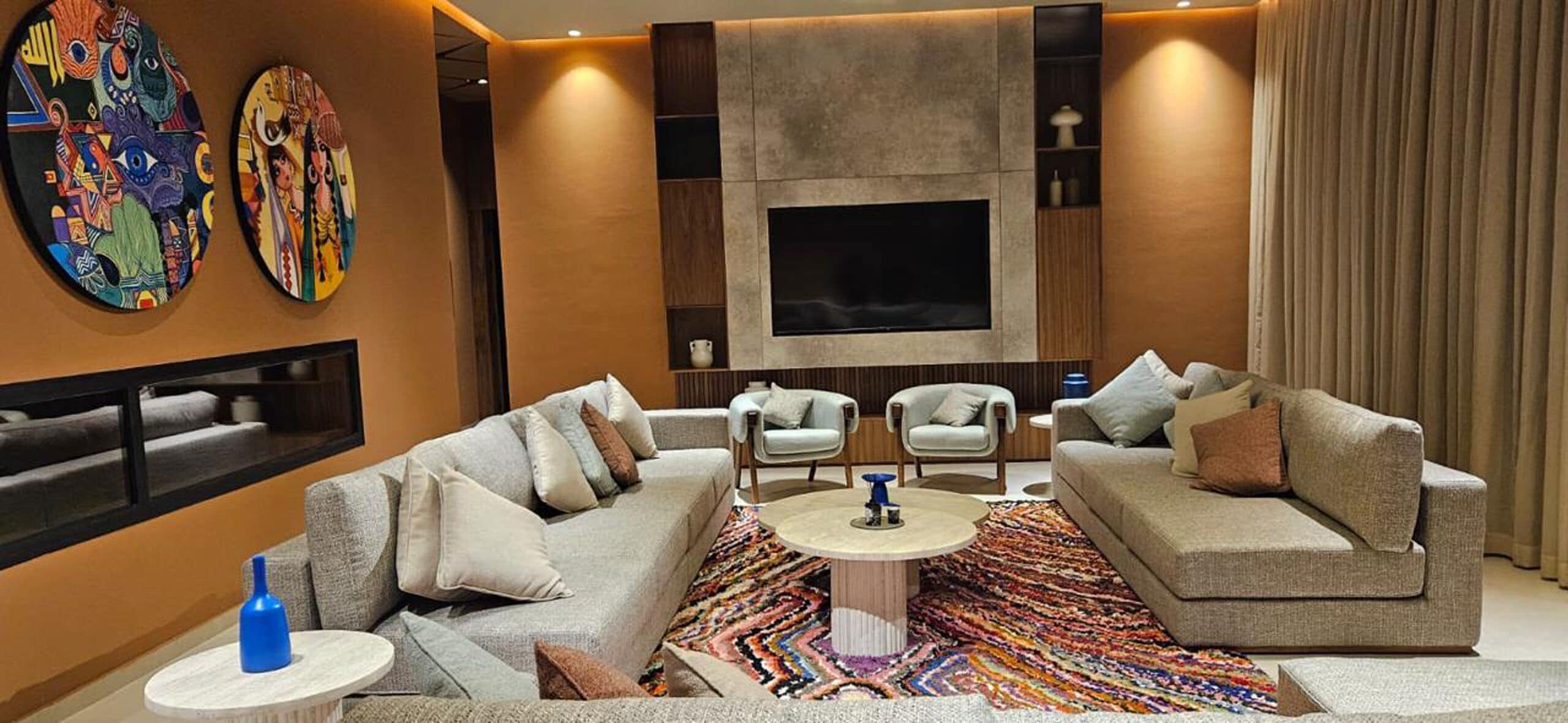 Uma sala de estar moderna com um sofá, uma mesa de centro e uma televisão de tela plana na parede.