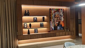 Un interior moderno con un panel de madera, una estantería con objetos decorativos y un cuadro grande.